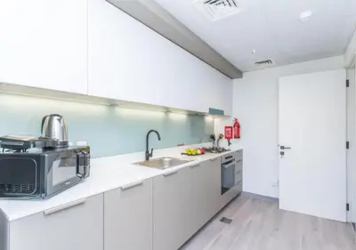 a white kitchen with a sink and a microwave at Classy 1BR in Midtown Access All Dubai Spots by Vibel in Dubai