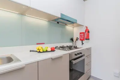 a white kitchen with a bowl of fruit on the counter at Classy 1BR Midtown Stay Near Miracle Garden by Vibel in Dubai