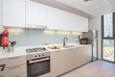 a kitchen with white cabinets and a sink and a stove at Cozy 1BR Midtown 20 Mins to Mall of Emirates by Vibel in Dubai