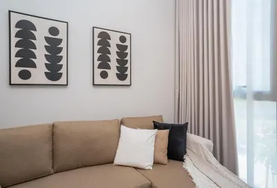 a couch in a living room with two pictures on the wall at Cozy 1BR Midtown 20 Mins to Mall of Emirates by Vibel in Dubai