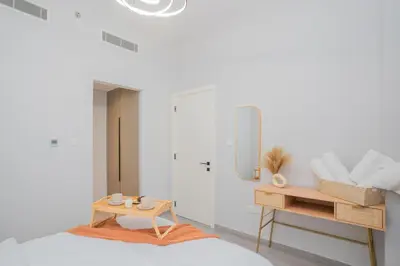 a white bedroom with a bed and a table at Cozy 1BR Midtown 20 Mins to Mall of Emirates by Vibel in Dubai