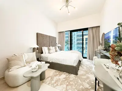 a white bedroom with a bed and a couch at Trophy Blissful Bend Studio in Meydan with Pool Views in Dubai