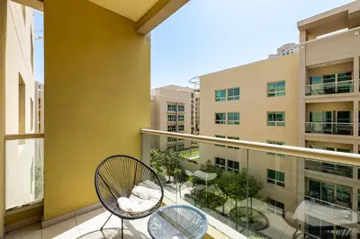 a balcony with two chairs and a building at 1BR The Greens Courtyard View in Dubai