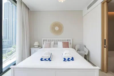 a white bedroom with a bed and a large window at Luxury at JBR Jumeirah Gate Tower 1 1 Bed in Dubai