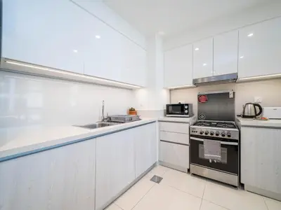 a kitchen with white cabinets and a stove top oven at Dubai Hills Elegant 1-Bed with Terrace in Dubai