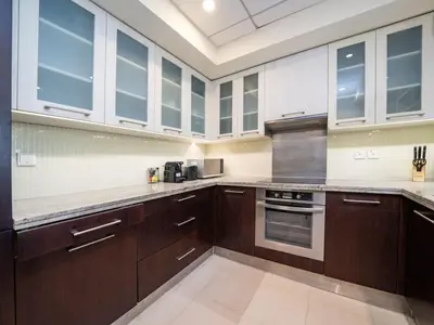 a large kitchen with wooden cabinets and stainless steel appliances at Downtown 1 Bed - Burj Khalifa Balcony View in Dubai