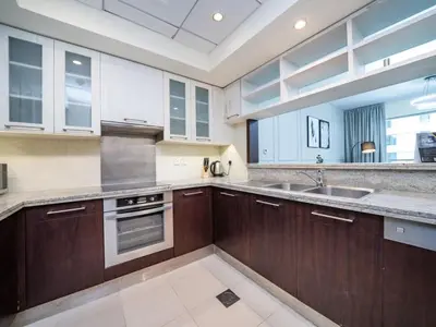 a kitchen with wooden cabinets and a sink at Downtown 1 Bed - Burj Khalifa Balcony View in Dubai