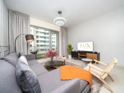 a living room with a gray couch and a tv at Downtown 1 Bed - Burj Khalifa Balcony View in Dubai