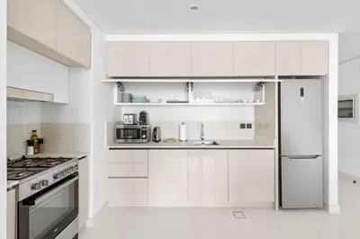 a white kitchen with white cabinets and a refrigerator at Silkhaus Marina View 1BDR Private Beach Access in Dubai