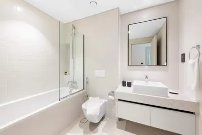 a bathroom with a sink and a toilet and a mirror at Silkhaus Marina View 1BDR Private Beach Access in Dubai