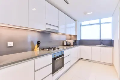 a kitchen with white cabinets and a stove top oven at 2 BR with Maid's Next to Dubai Mall Mada Residences in Dubai