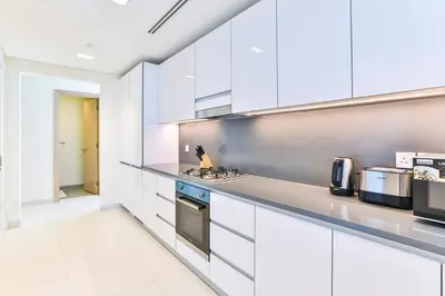 a white kitchen with white cabinets and appliances at 2 BR with Maid's Next to Dubai Mall Mada Residences in Dubai