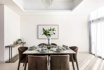 a dining room table with chairs and a vase of flowers at 2 BR with Maid's Next to Dubai Mall Mada Residences in Dubai