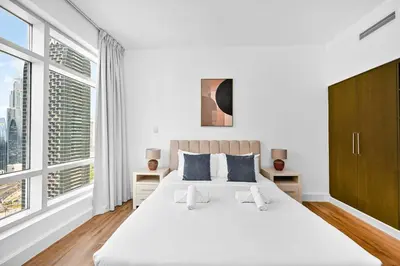 a white bedroom with a large bed and large windows at Prime Downtown Burj Khalifa I Sleeps 8 in Dubai