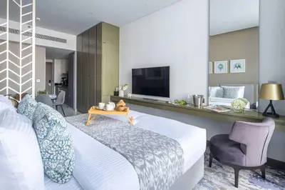 a bedroom with a bed and a tv and a chair at Frank Porter - Damac Maison Prive B in Dubai