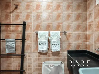 a bathroom with a sink and two towels on a wall at Rare Holiday Homes - Near City Center Ma'eisem - Pool view - Crescent Tower A - R706 - IMPZ in Dubai