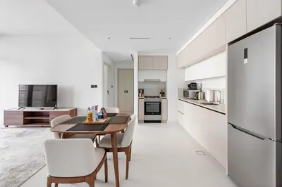 a kitchen with a wooden table and white cabinets at Silkhaus 1BDR with Private Beach Marina Vista in Dubai