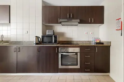 a kitchen with brown cabinets and a microwave at 2BR Torch Tower High Floor Dubai Marina in Dubai
