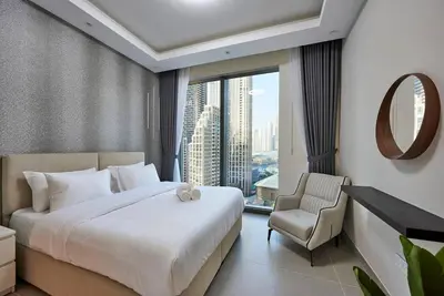 a bedroom with a bed and a chair and a window at 3BR Burj Khalifa Fountain Views Forte 1- 18th floor in Dubai