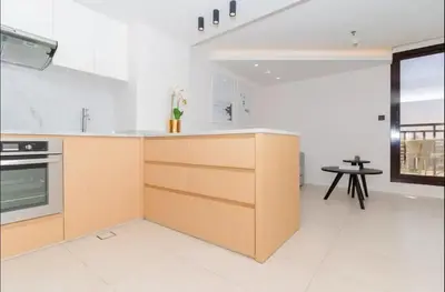 a kitchen with white walls and wooden cabinets and a table at AWS Holiday Homes - Oasis in the Palm in Dubai