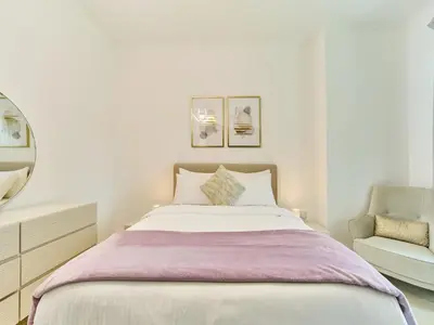 a white bedroom with a bed and a chair at Golden homes Residences Tower 05 1BR CITY VIEW Near Dubai mall & burj khalifa in Dubai