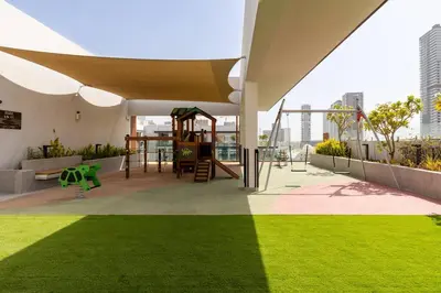 a playground on the roof of a building with green grass at Waves - Tranquil Living 2BR Apt in JVC with City Views in Dubai