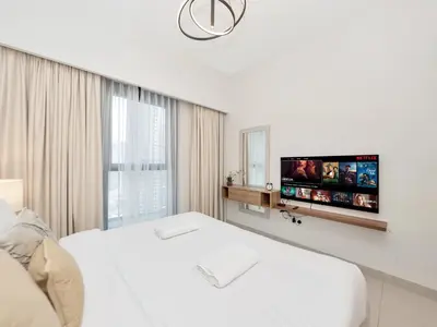 a white bedroom with a bed and a flat screen tv at 2BR Burj Khalifa & Fountain Views Burj Crown 39th Floor in Dubai