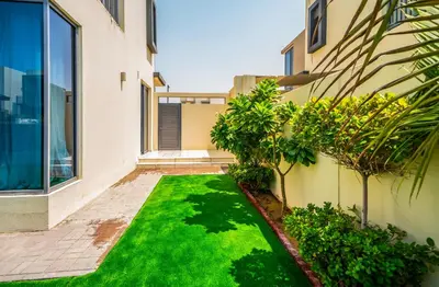 a yard with green grass next to a building at NewArabian Dubai HillsMaple Villa in Dubai