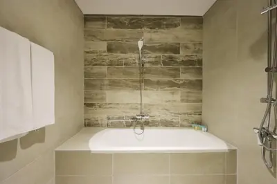 a bath tub in a bathroom with a stone wall at Livbnb-Tranquil 1B Steps to PalmBoardwalk Sea View in Dubai