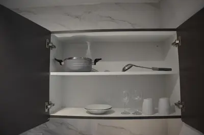 a kitchen shelf with a pot and glasses on it at Ista Vacation Homes Rental LLC KARAMA in Dubai