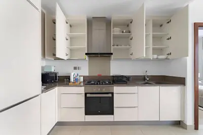a kitchen with white cabinets and a stove top oven at Silkhaus Modern Dubai Marina 1BDR Marina Gate in Dubai