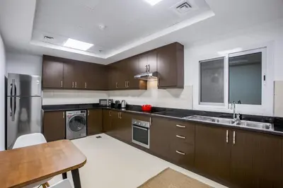 a kitchen with wooden cabinets and a stainless steel refrigerator at Blueground Sheikh Zayed Rd pool gym DXB-545 in Dubai