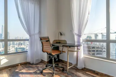 a desk and chair in a room with windows at Blueground South Ridge Tower 1 city view pool DXB-1409 in Dubai