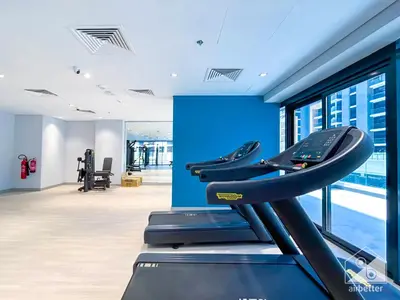 a gym with a treadmill and a blue wall at Charming Studio with Balcony in Azizi Riviera in Dubai