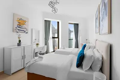 a white bedroom with two white beds and a window at Skyline Views 2BR Near Burj Khalifa & Dubai Mall with Pool Access in Dubai