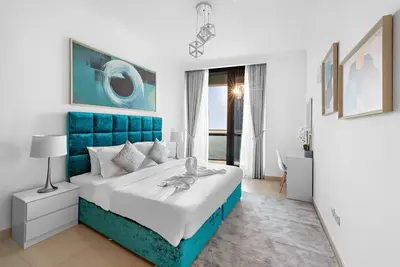 a white and blue bedroom with a blue headboard at Skyline Views 2BR Near Burj Khalifa & Dubai Mall with Pool Access in Dubai