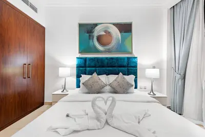 a bedroom with a white bed with a blue headboard at Skyline Views 2BR Near Burj Khalifa & Dubai Mall with Pool Access in Dubai