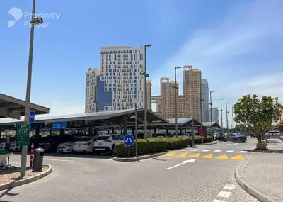 a parking lot with cars parked in front of a building at Amazing Studio Apartment in The Crescent A Tower IMPZ in Dubai