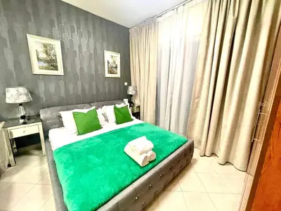 a bedroom with a bed with green sheets and towels at Amazing Studio Apartment in The Crescent A Tower IMPZ in Dubai