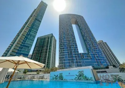 a swimming pool in front of two tall buildings at Elegant Beachfront Living at Al Bateen in Dubai