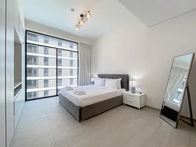 a bedroom with a bed and a large window at Wilton Terrace Charm- Stylish 1-Bedroom in MBR City With a Pool View in Dubai