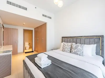 a bedroom with a large bed with white sheets at Luxury Meydan Escape Condo with City Views in Dubai