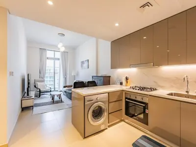 a kitchen with a washer and dryer and a living room at Luxury Meydan Escape Condo with City Views in Dubai