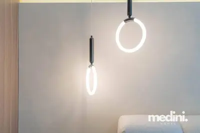 two lights hanging from a wall next to a chair at Azizi Riviera - 12min from Downtown in Dubai