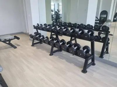 a rack of dumbbells in a gym with a mirror at Azizi Riviera - 12min from Downtown in Dubai