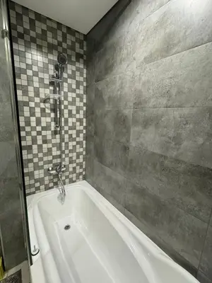 a bath tub in a bathroom with a tile wall at Capsule Room in Business Bay Near Downtown in Dubai