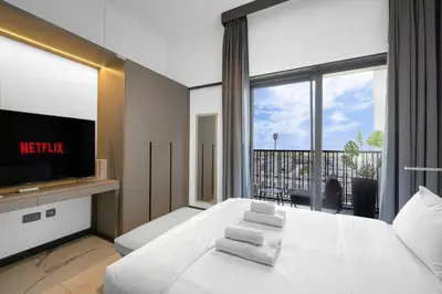 a bedroom with a bed with a television and a balcony at Sukoon's Elegant Suite in Dubai