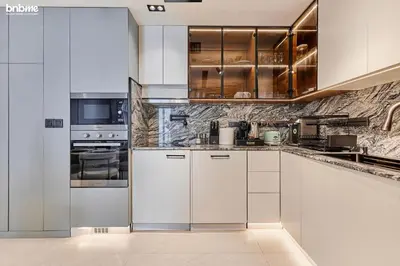 a kitchen with white cabinets and stainless steel appliances at bnbmehomes - Silverene Tower in Dubai