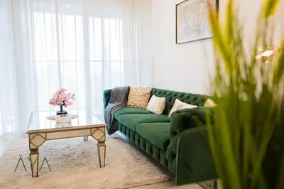 a green couch in a living room with a table at Elegant 1BR Retreat with Rooftop Pool in JVC By ĀYA Boutique in Dubai