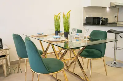 a glass table with green chairs in a kitchen at Elegant 1BR Retreat with Rooftop Pool in JVC By ĀYA Boutique in Dubai